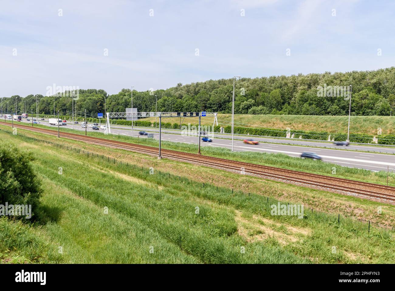 Autostrada parallela ai binari ferroviari nella campagna olandese in una giornata di sole estate Foto Stock