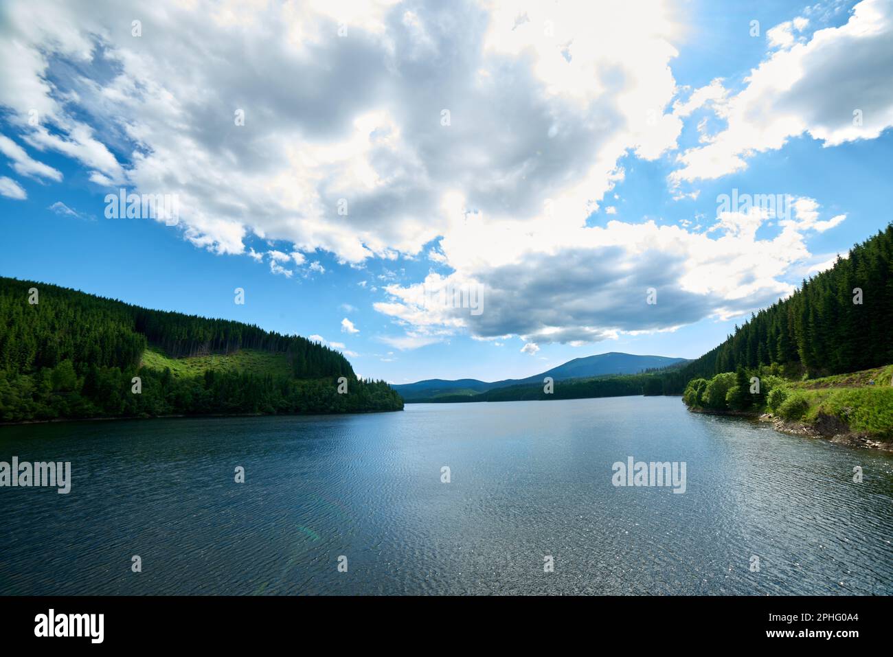 Un lago tranquillo è situato in un paesaggio idilliaco, circondato da lussureggianti colline ondulate, Carpazi montagne Foto Stock
