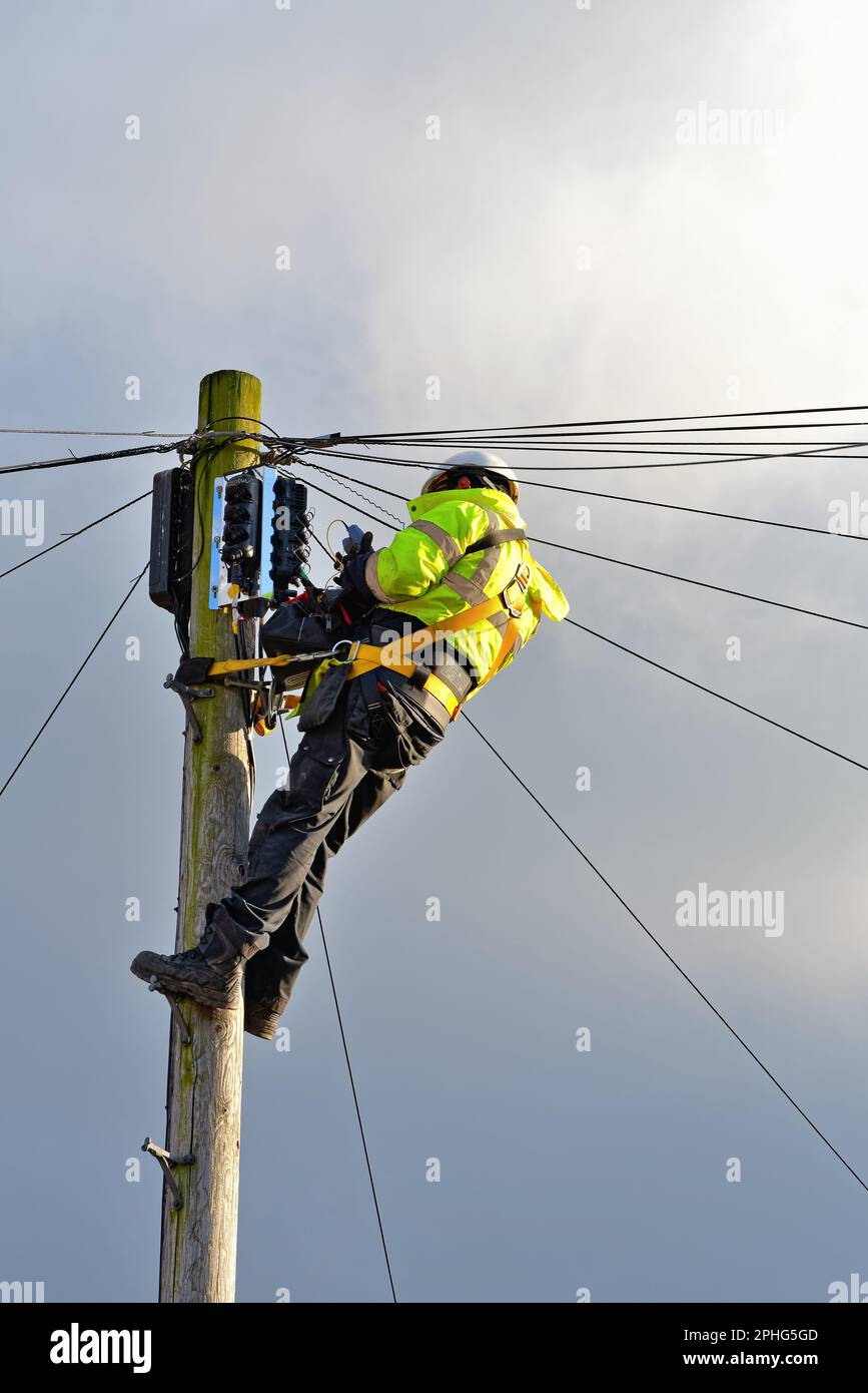 Un ingegnere di British Telecoms che installa il cavo a fibra ottica alla parte superiore di un palo telefonico Inghilterra Regno Unito Foto Stock
