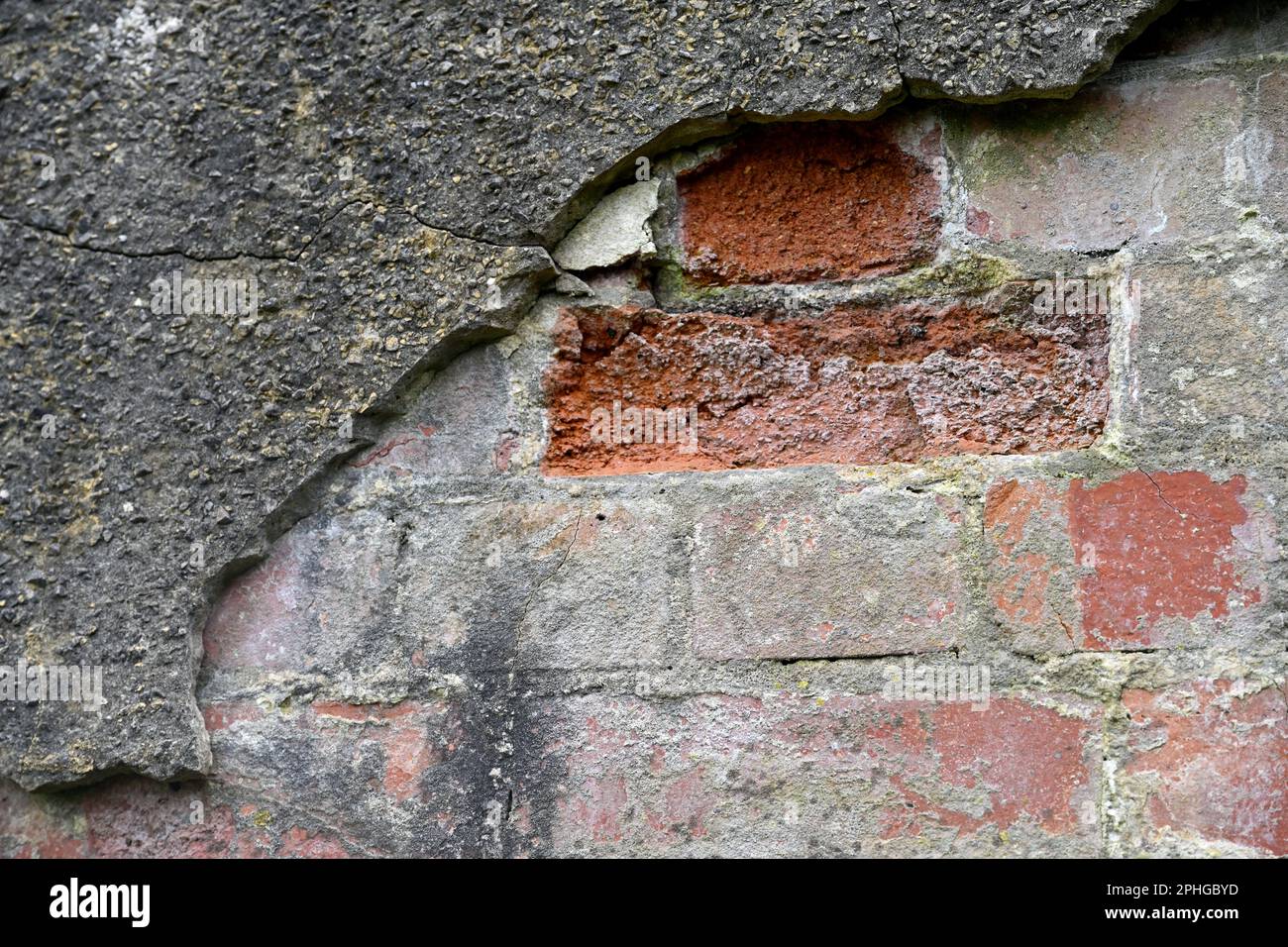 Muro di mattone reso con un cemento duro che sta rompendo e cadendo via Foto Stock