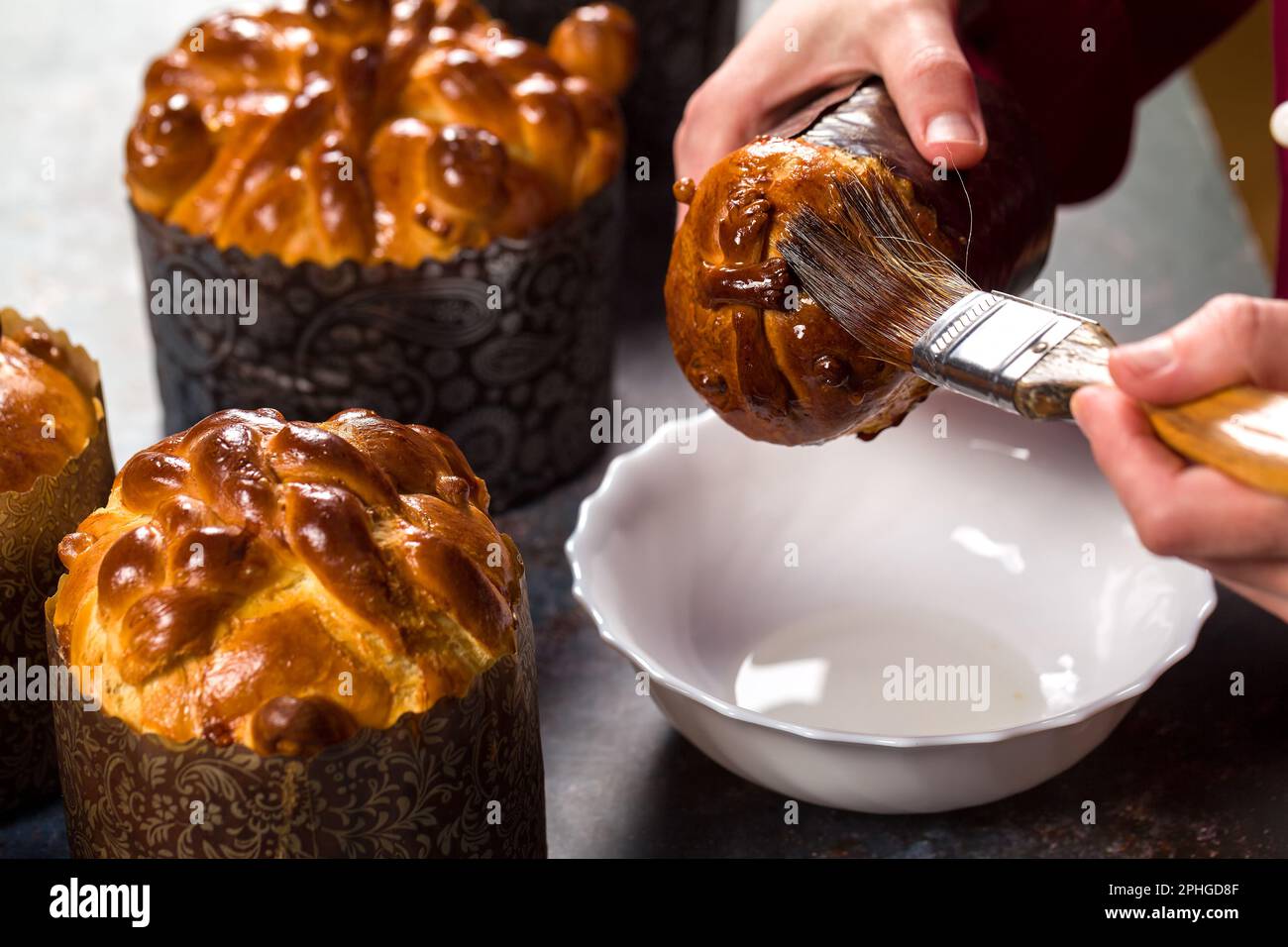 Lo chef di pasticceria decora la torta di Pasqua appena sfornata con sciroppo di zucchero e una morbida nappina Foto Stock