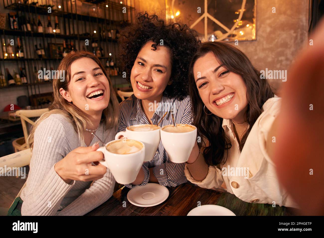 Tre amici femminili prendono selfie mentre si divertono in caffetteria. Felice sorridente ragazze guardando la macchina fotografica Foto Stock