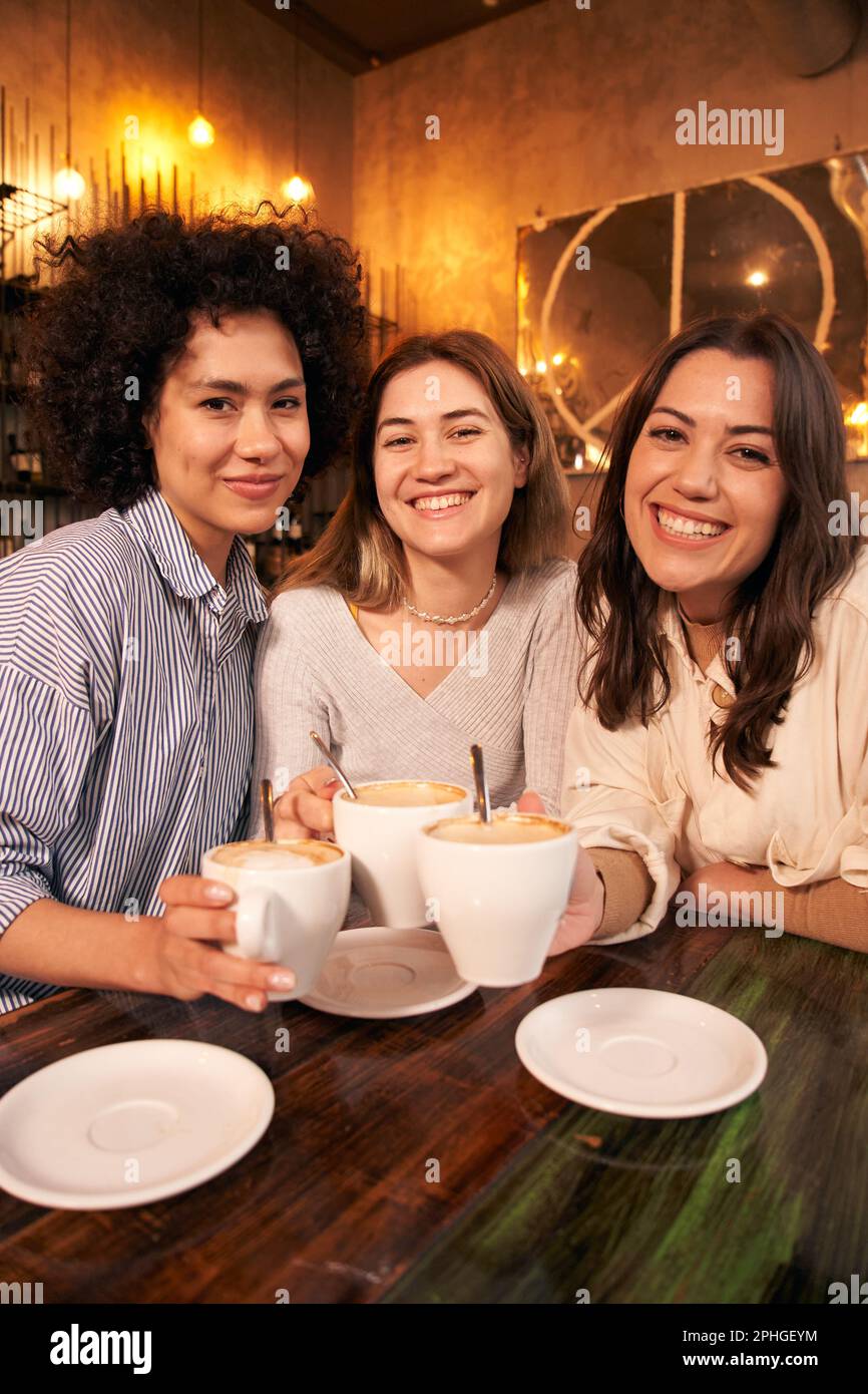 Verticale tre amici femmina prendere selfie avendo divertente caffetteria. Ragazze sorridenti felici che guardano la macchina fotografica Foto Stock