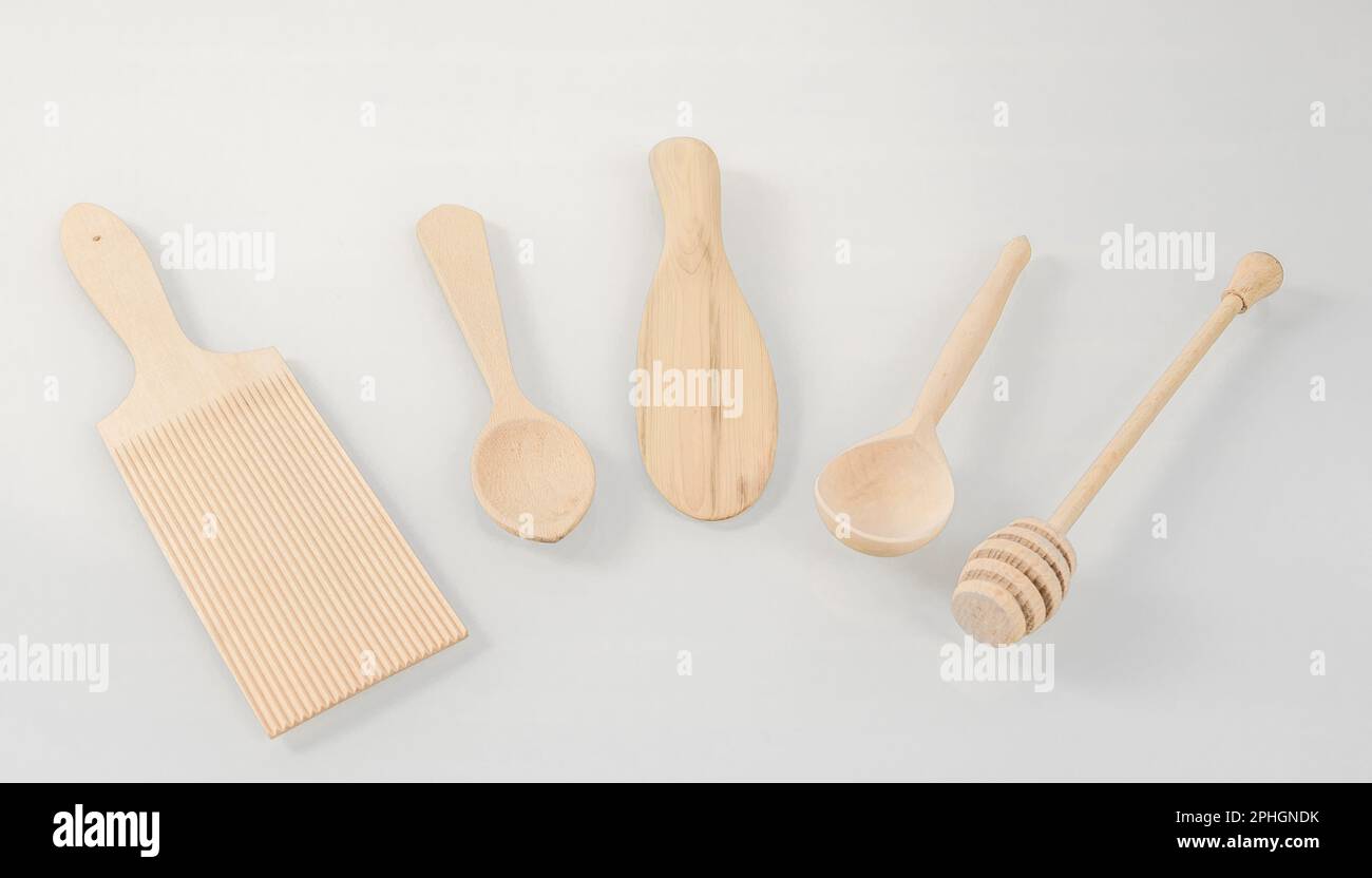 Utensili da cucina in legno. Vari utensili da cucina in legno disposti a semicerchio su uno sfondo chiaro. Foto Stock