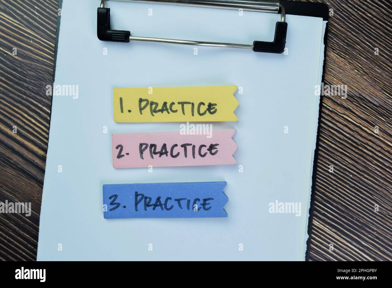 Concetto di pratica, pratica, pratica scrivere su note appiccicose isolate su tavola di legno. Foto Stock
