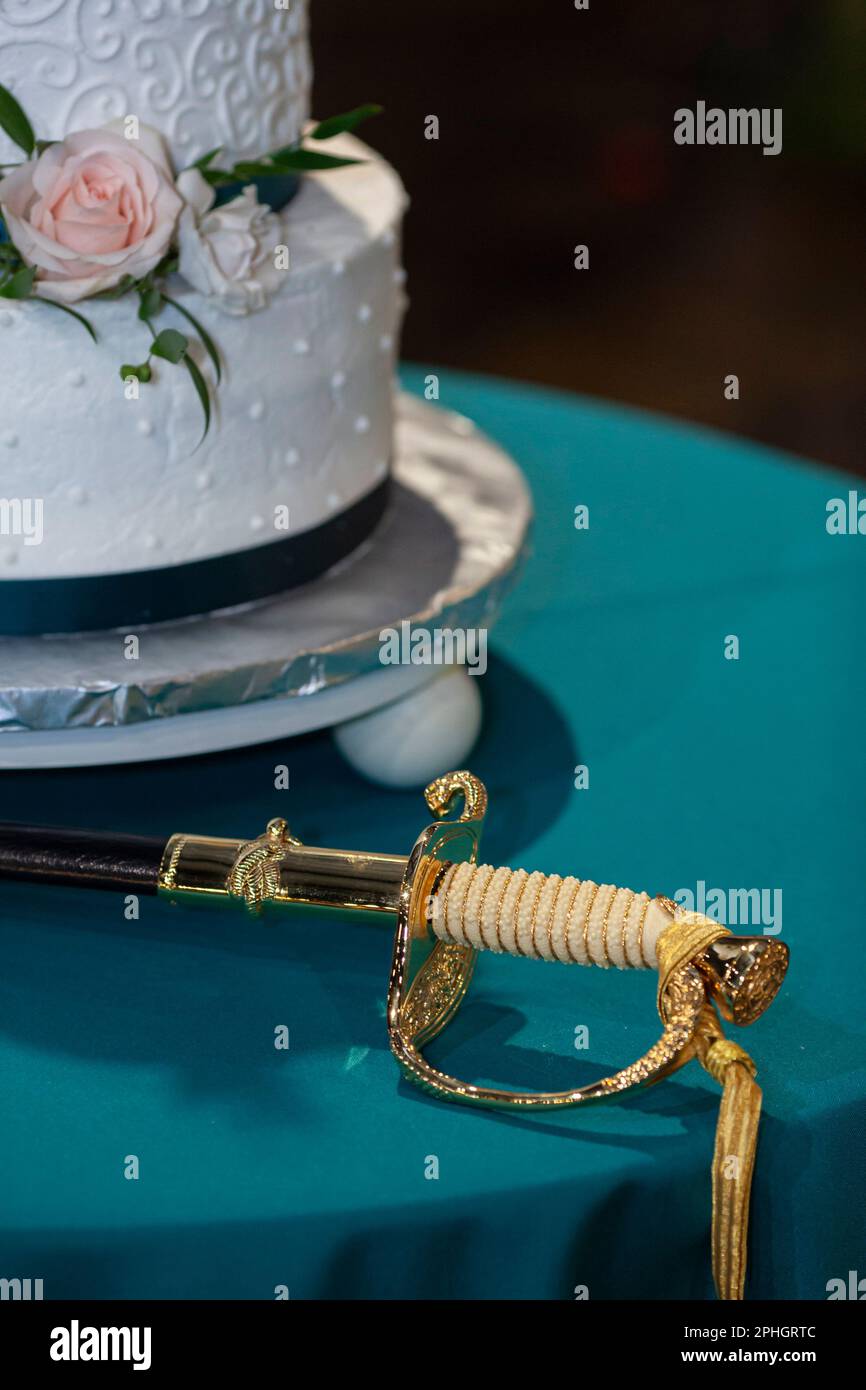 Particolare della torta nuziale e della spada per un ricevimento militare di nozze. Foto Stock