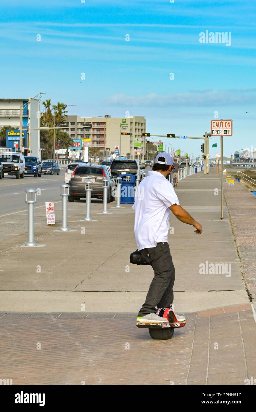 Galveston, Texas, Stati Uniti d'America - 2023 febbraio: Persona in sella a uno skateboard a ruote sul lungomare della città. Foto Stock