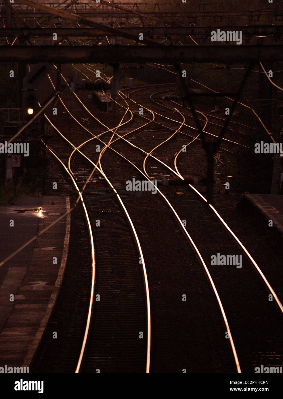 Binari ferroviari che riflettono il caldo bagliore del tramonto, la stazione ferroviaria di Ashburys si trova a Openshaw, la linea Manchester-Glossop Foto Stock