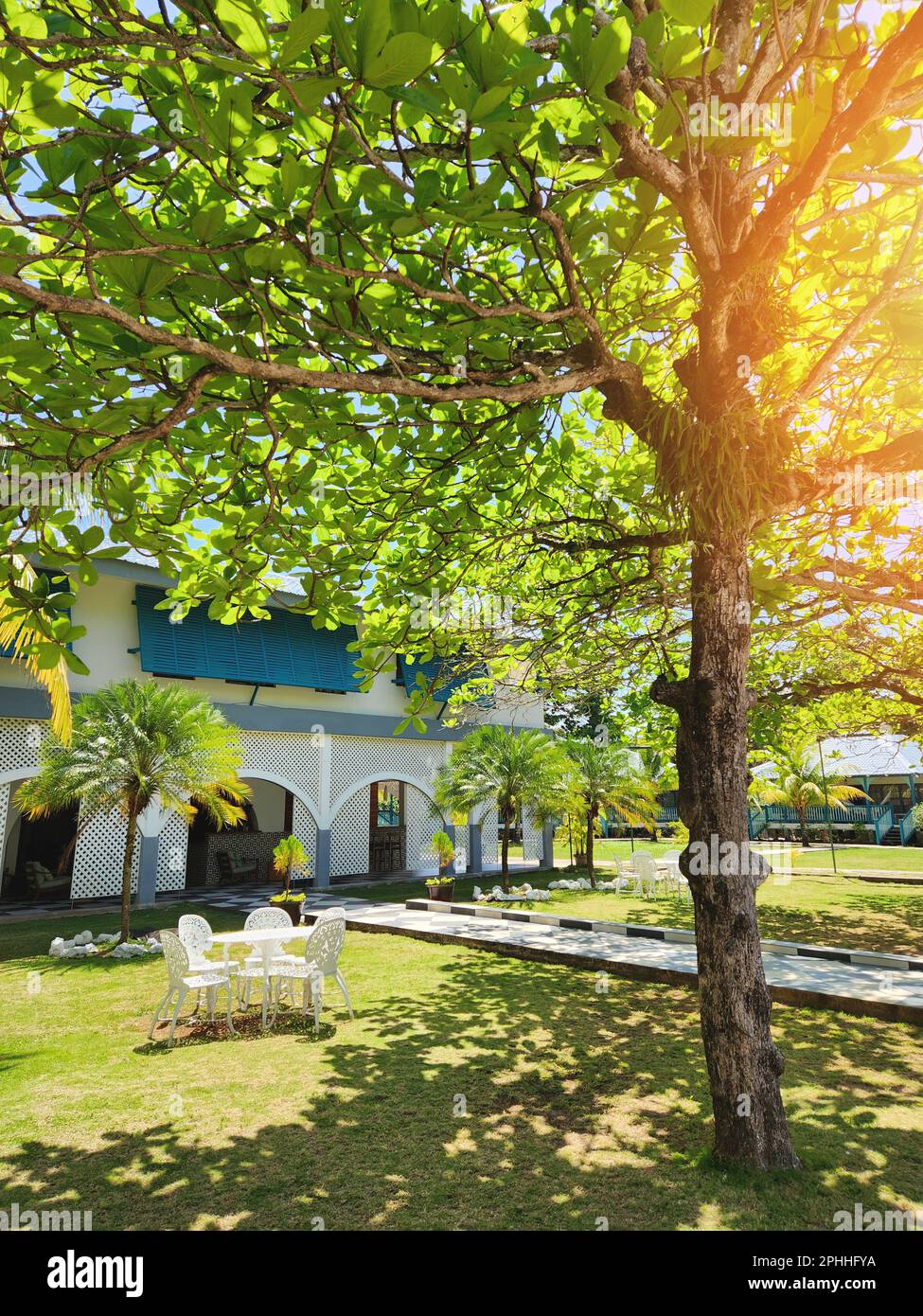 Edificio in legno di stile coloniale all'ombra di alberi tropicali Foto Stock