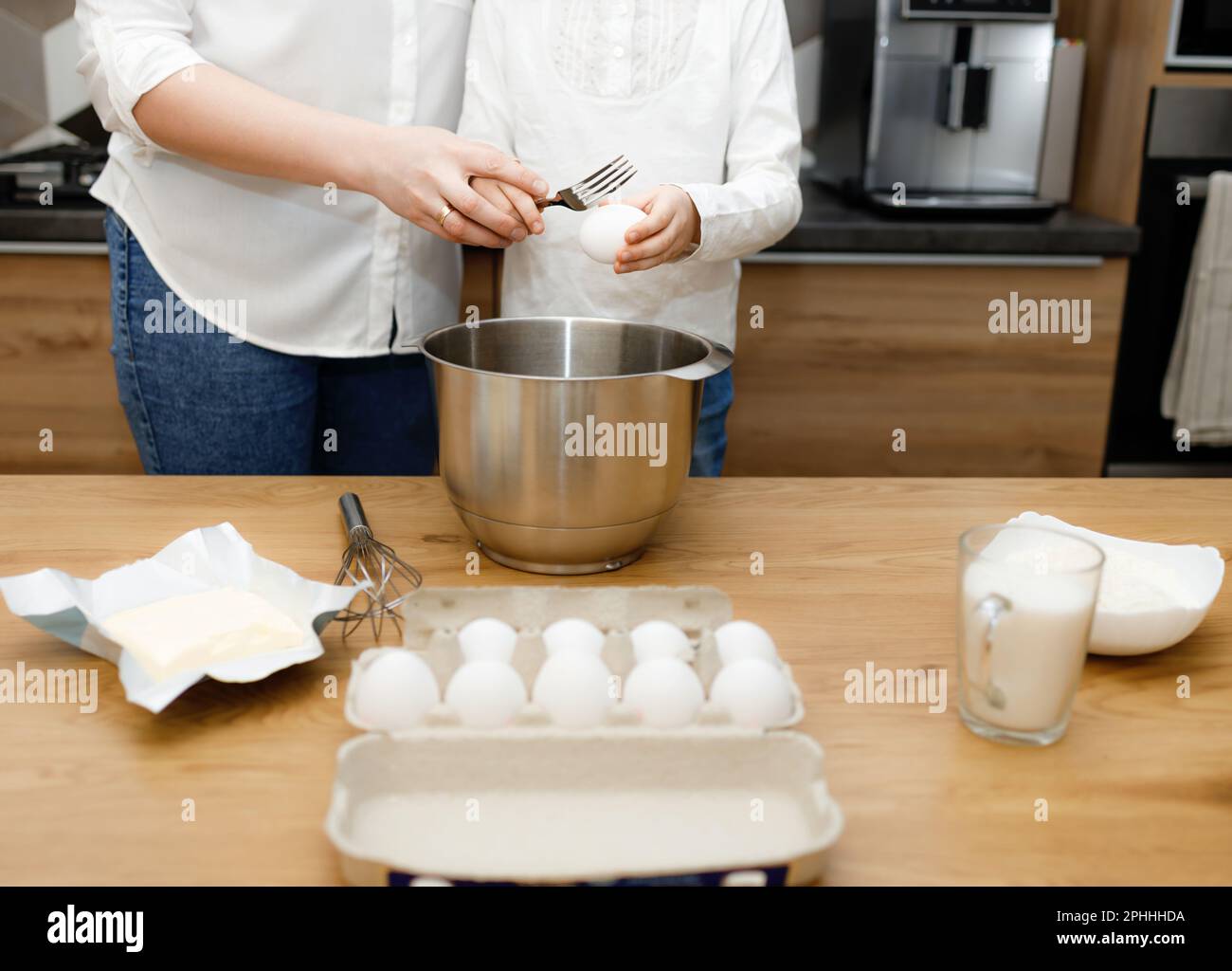 Madre insegna a sua figlia cracking, sbattendo le uova, preparando e mescolando pasta in cucina moderna. Piccolo aiuto. Divertirsi stare insieme. Famiglia ac Foto Stock