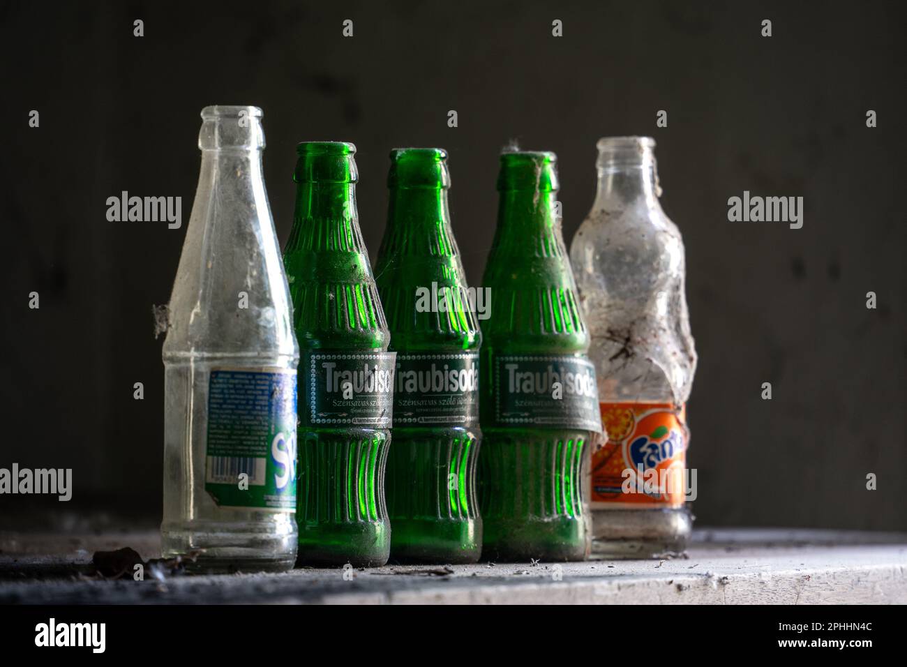 Primo piano delle bottiglie di soda vuote lasciate dietro con polvere pesante e rete ragno su di esse Foto Stock