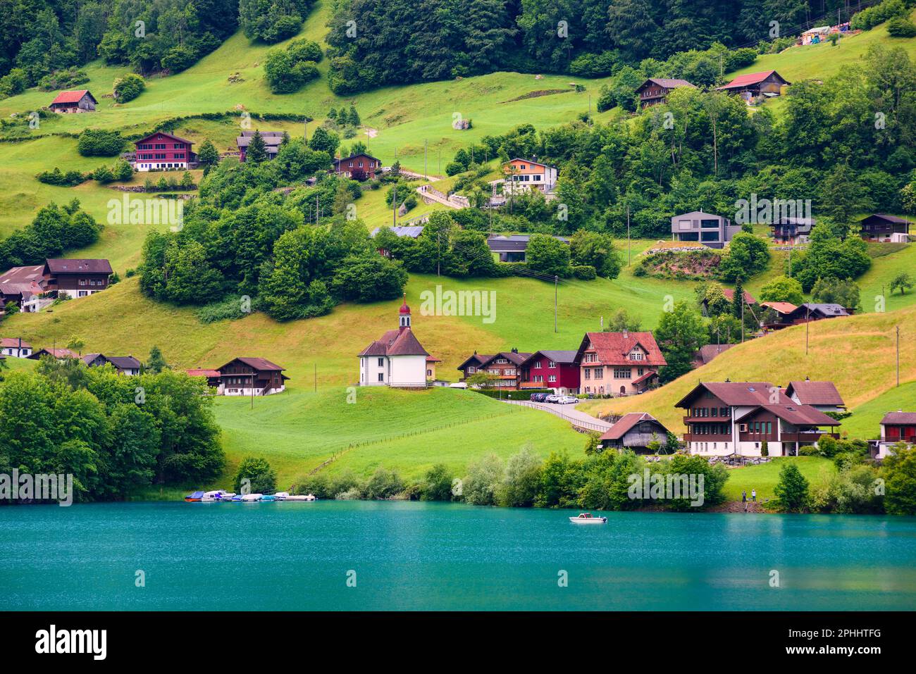 Acque turchesi e lussureggianti prati verdi nel pittoresco villaggio di Burglen, il lago di Lungern, le montagne delle Alpi svizzere, la Svizzera centrale Foto Stock