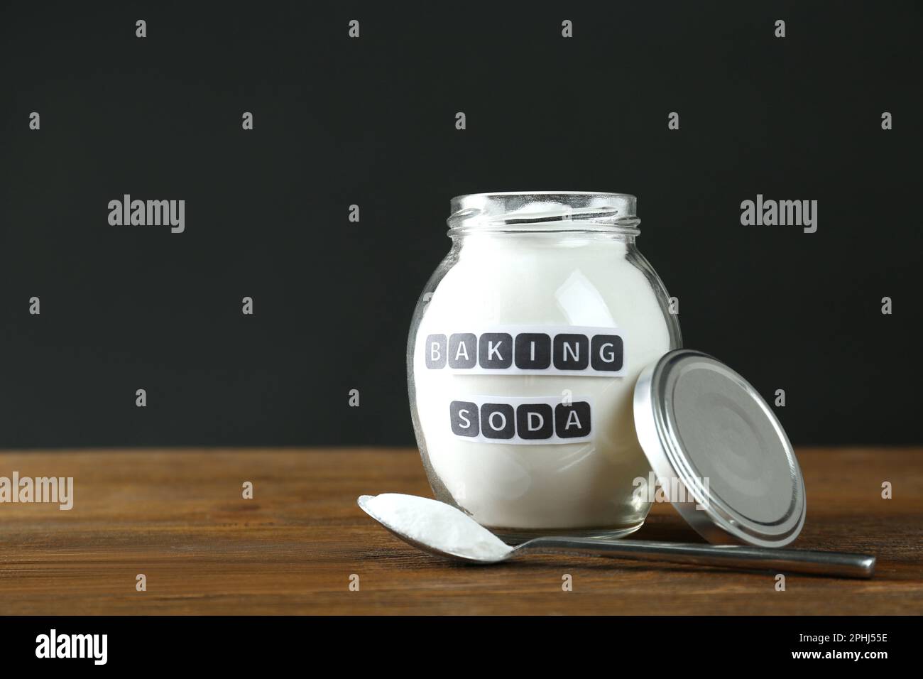 Vasetto e cucchiaio con bicarbonato su tavolo di legno. Spazio per il testo Foto Stock