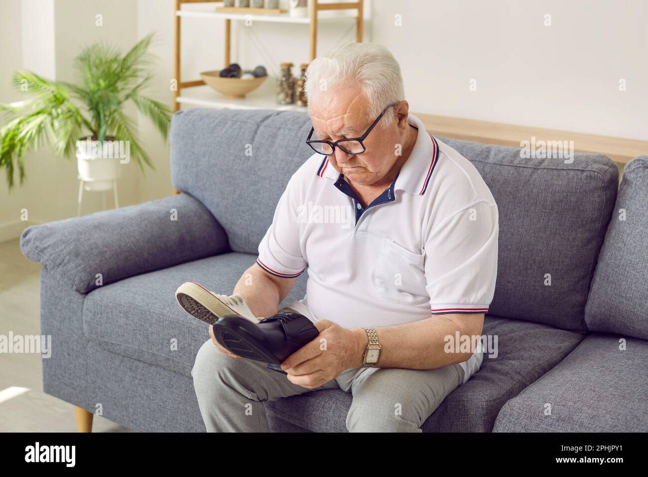 Uomo anziano che sceglie tra scarpe classiche e moderne Foto Stock