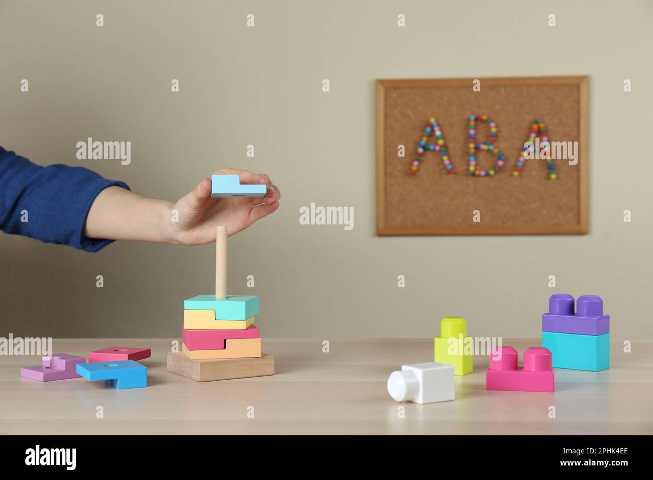 Bambino che gioca con la piramide giocattolo al tavolo di legno all'interno, primo piano. Concetto di terapia ABA Foto Stock