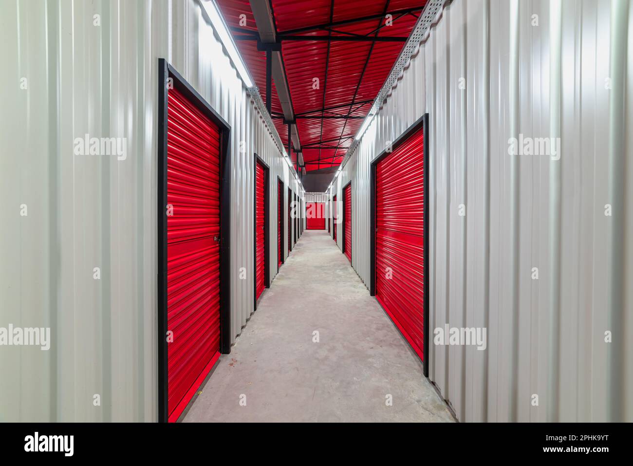 Corridoio dell'unità di self-storage con porte rosse. Unità di stoccaggio a noleggio Foto Stock