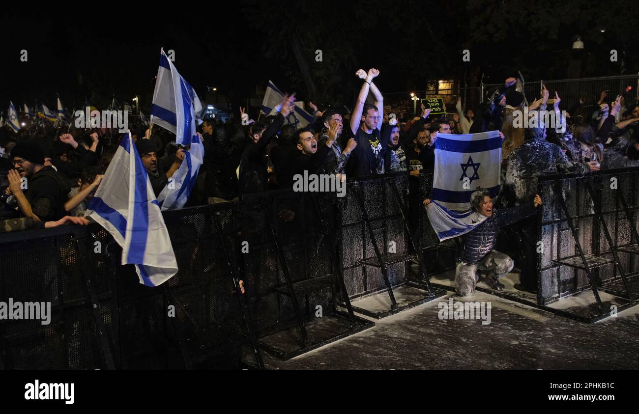 I manifestanti anti anti-governativi detengono bandiere israeliane mentre la polizia israeliana utilizza un cannone ad acqua per disperderle durante una manifestazione al di fuori della casa privata di PM Benjamin Netanyahu in risposta al licenziamento del ministro della Difesa Yoav Galant dopo aver invitato il governo a fermare le sue controverse riforme giudiziarie il prossimo marzo 26, 2023 a Gerusalemme, Israele. Foto Stock