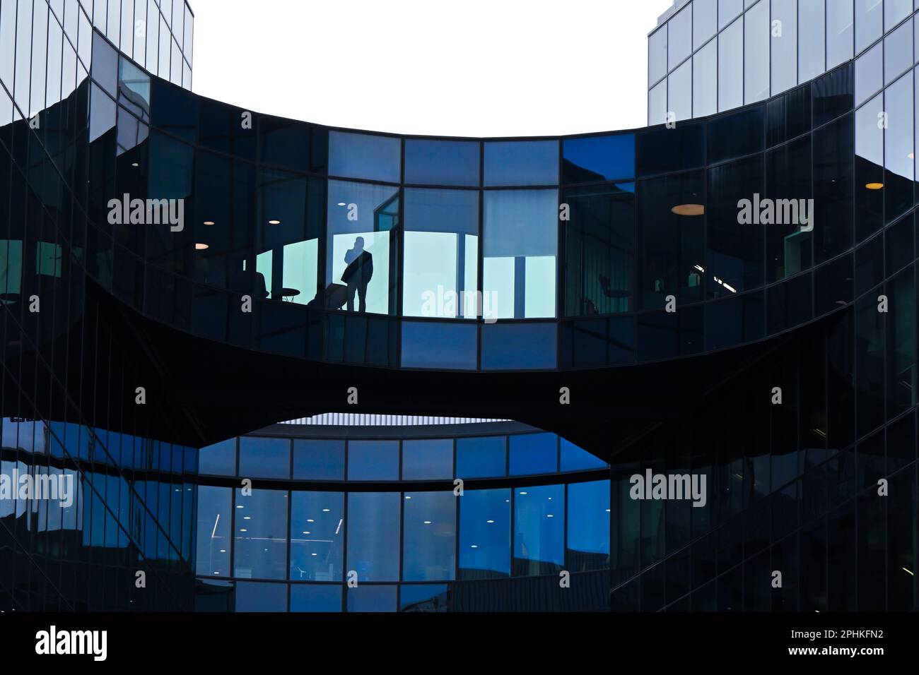 Un lucernario di vetro con la silhouette di un uomo che cammina e parla al telefono Foto Stock