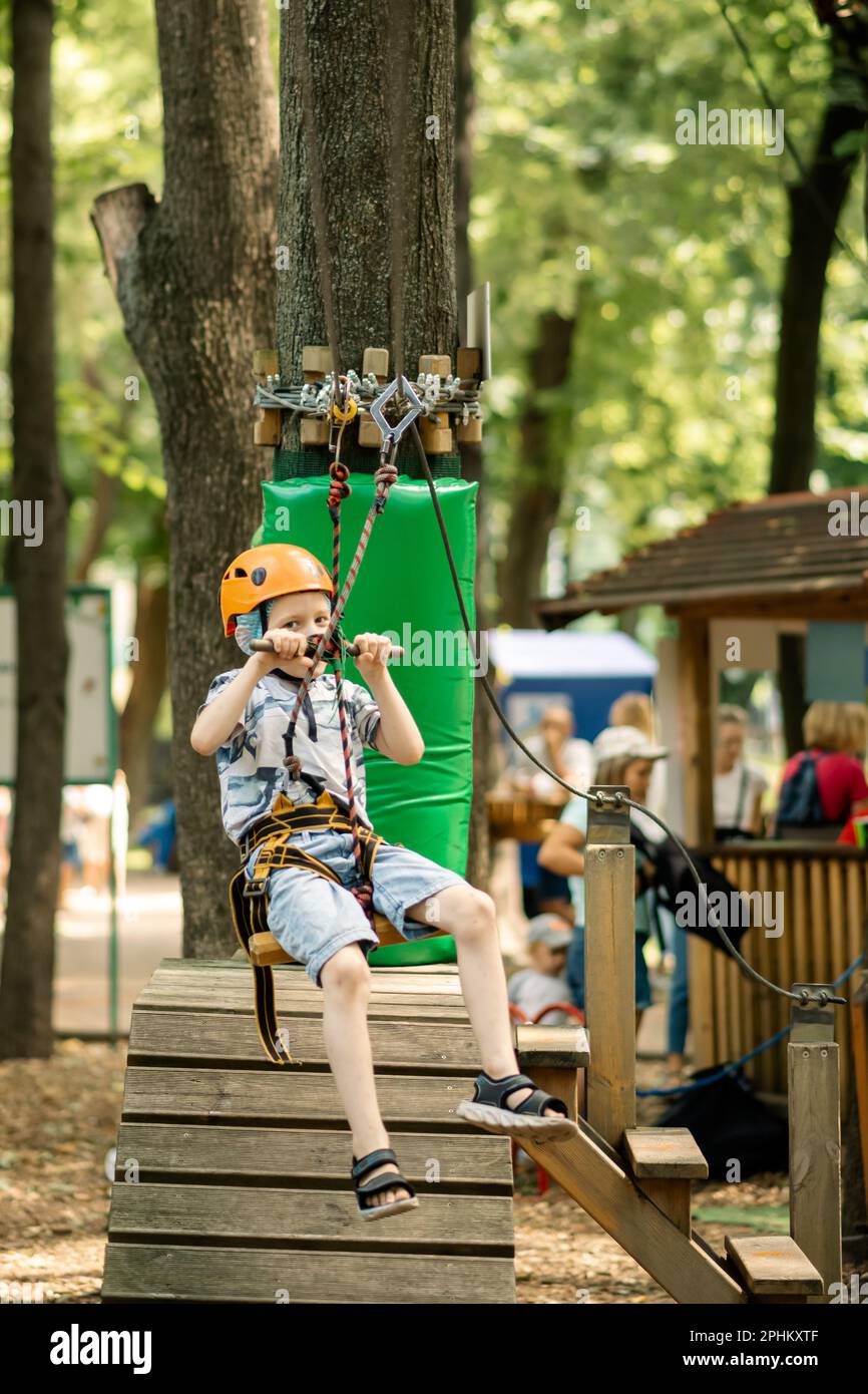 Un ragazzo è appeso sulla linea nel parco funi. Animazione sportiva per un bambino, riposo attivo. Foto Stock