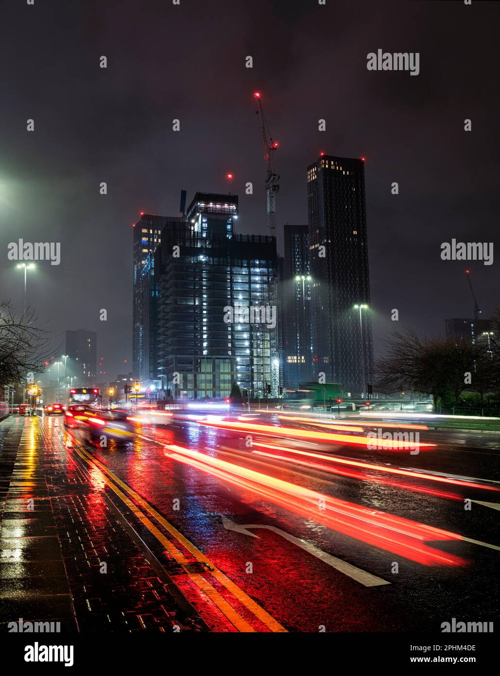 Torri e grattacieli in vetro, nuove costruzioni e costruzioni nella città inglese di Manchester, con luci soffuse di auto durante l'ora di punta Foto Stock