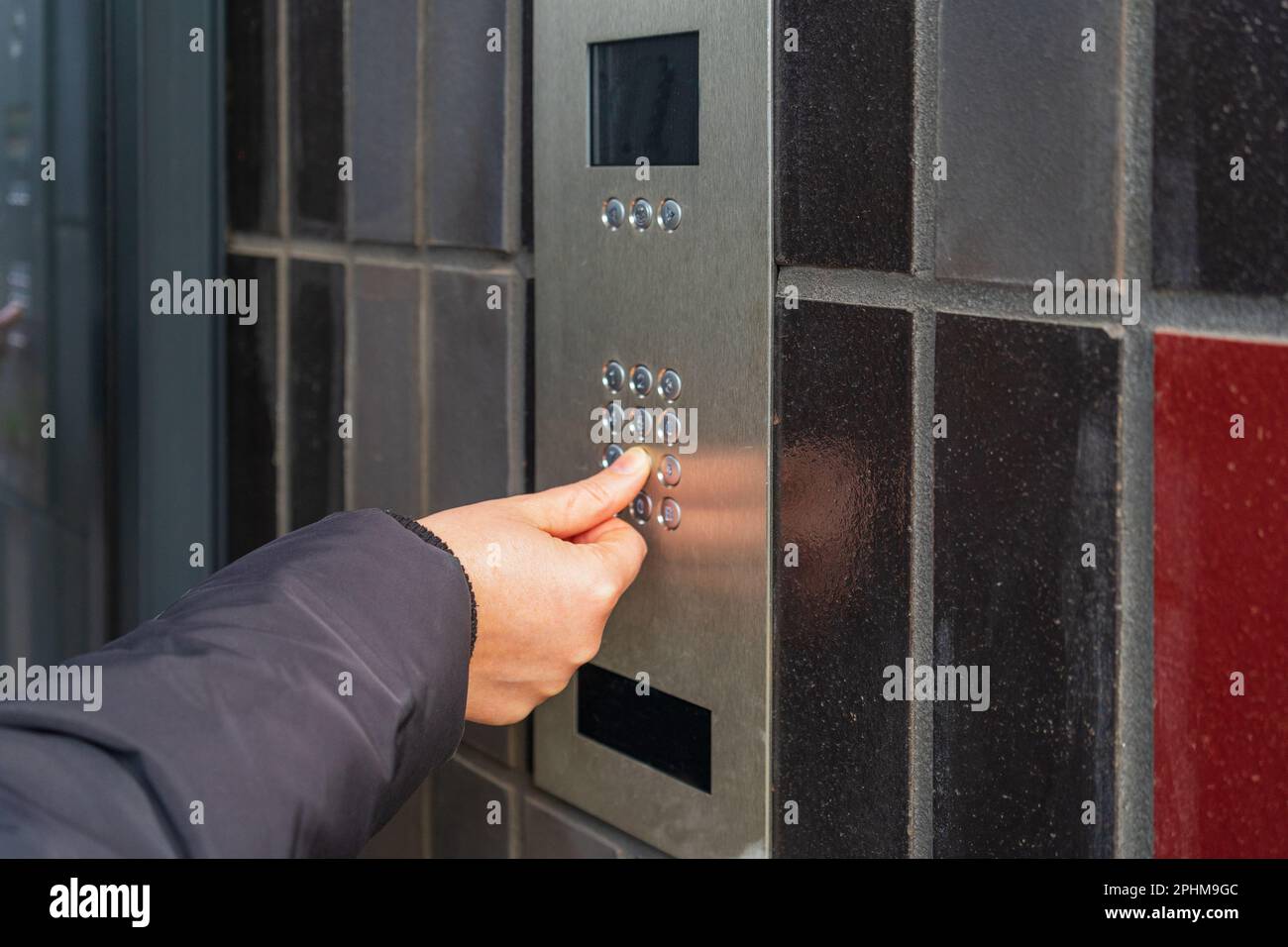 Sistema di casa sicuro, pressione della mano sulla tastiera dell'interfono, utilizzo di telefono della porta, telefono della porta, telefono dell'entryphone, chiamata videofoniera, Campanello elettronico digitale Foto Stock