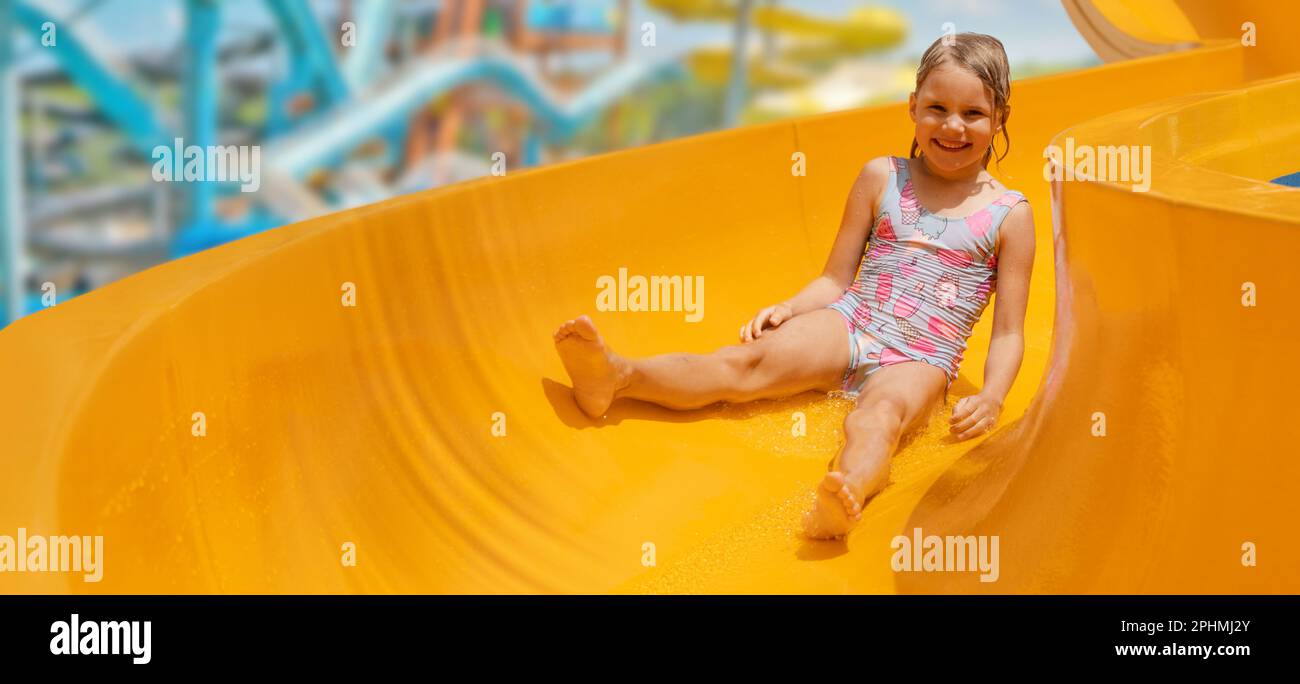 bambino felice sullo scivolo al parco acquatico all'aperto. banner con spazio di copia Foto Stock