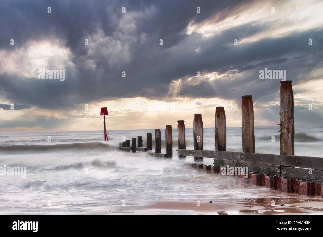 Frangiflutti sotto un cielo nuvoloso alla spiaggia di Redcar con l'indicatore leggermente inclinato. Foto Stock