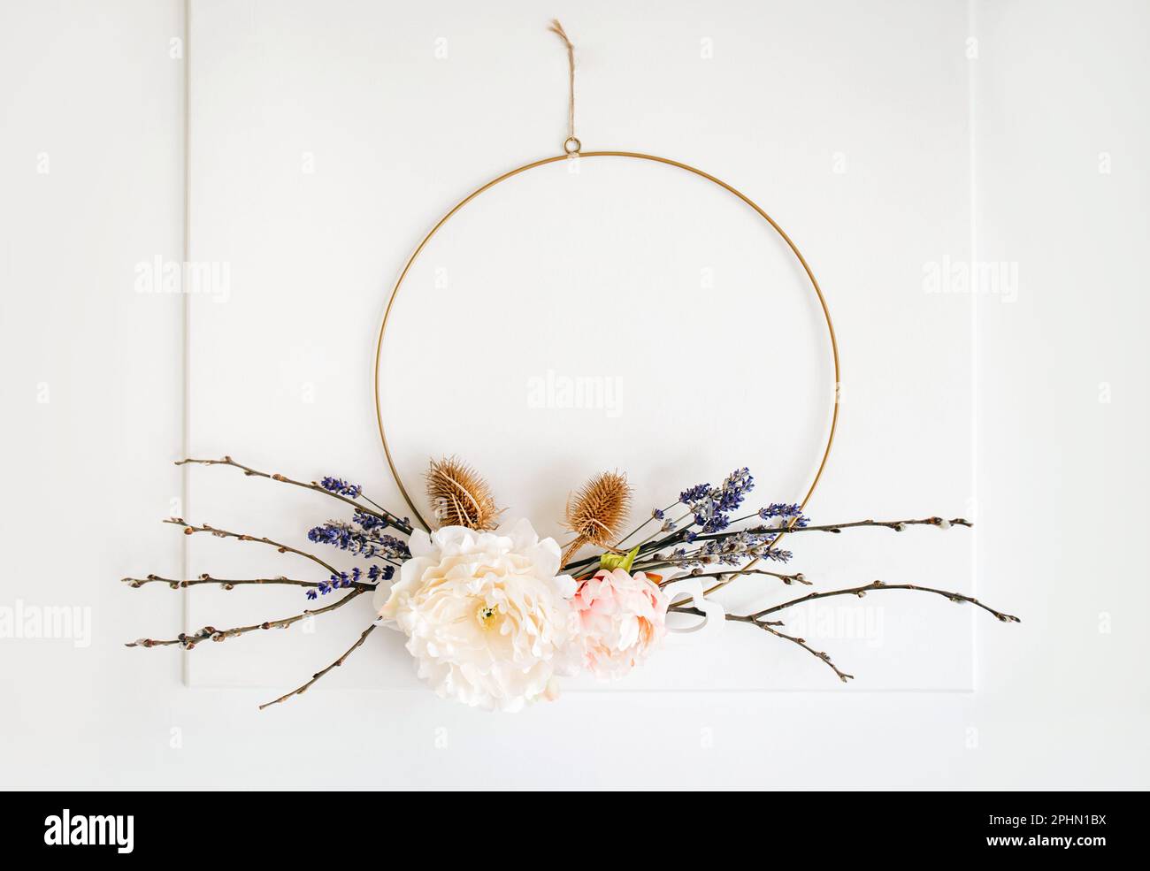 Wreath di disposizione floreale a tema della molla fatta a mano appeso alla porta bianca domestica per la decorazione. Telaio ad anello rotondo in metallo. Foto Stock