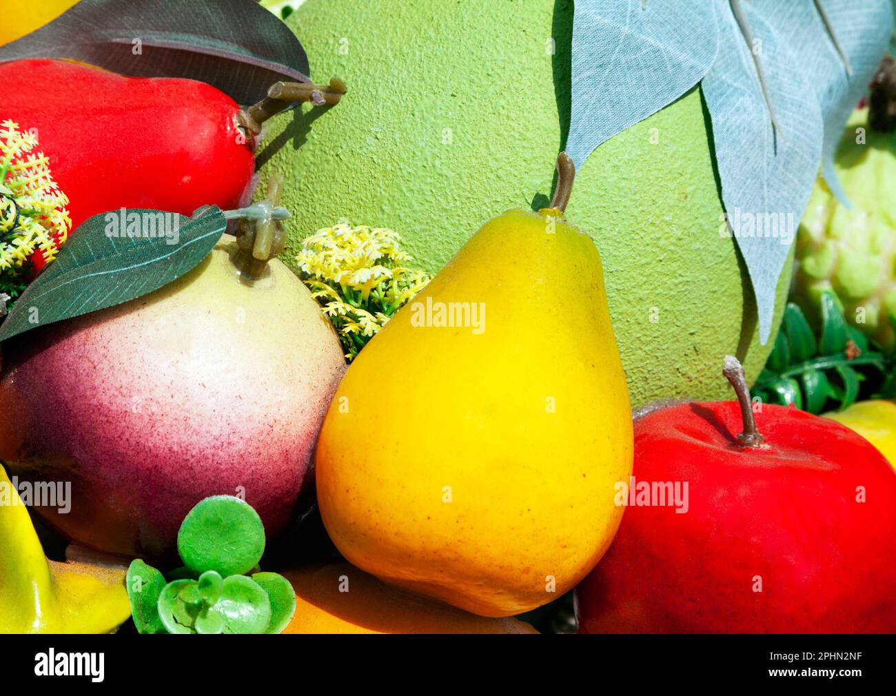 Gruppo di vari falsi frutti tra cui pere, una mela, un pomelo e una mela stella utilizzati come decorazione in un mercato. Mucchio di cibo di plastica appiccicoso in una supe Foto Stock