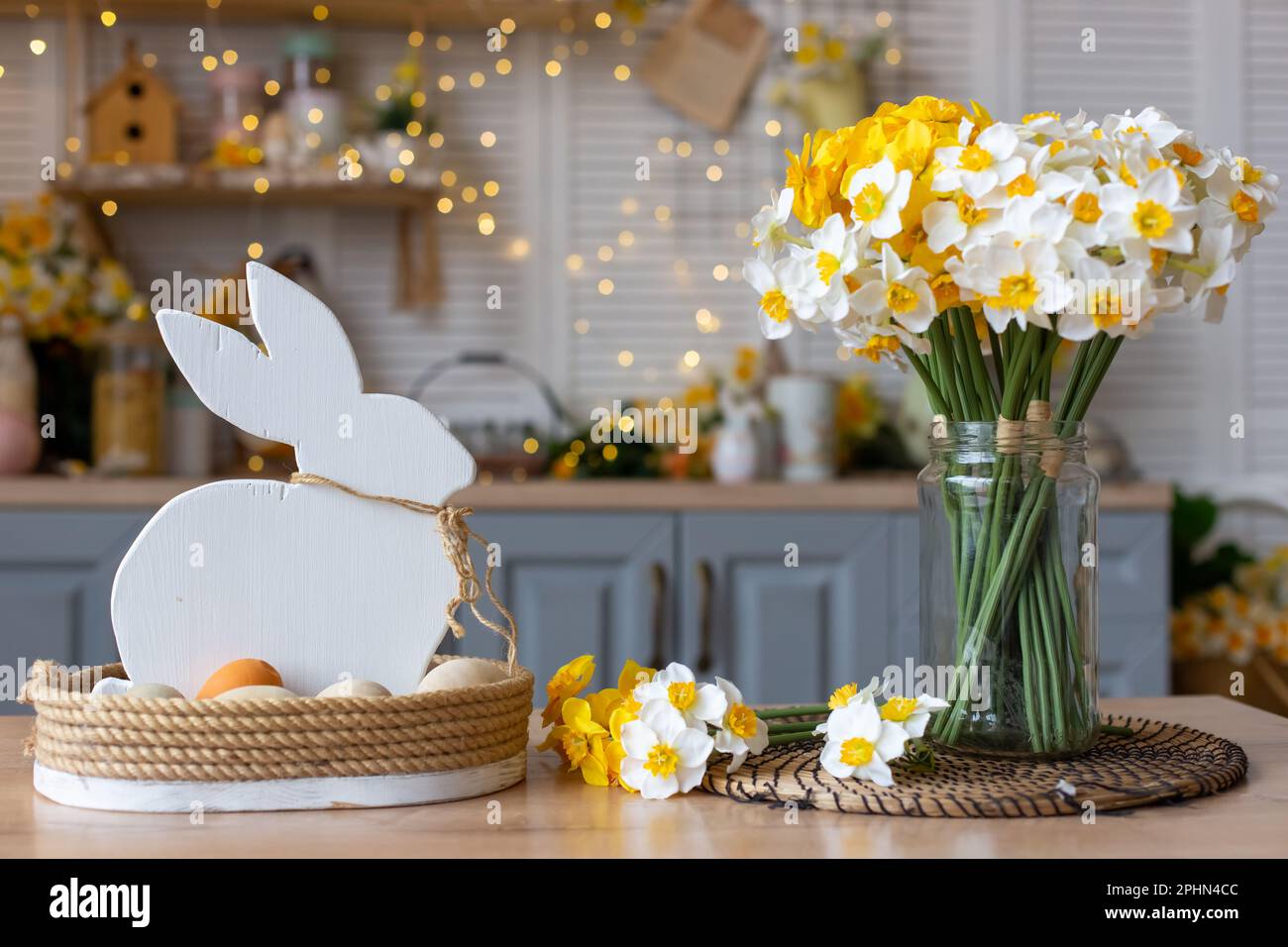 Sul tavolo si trova un cesto con un coniglio bianco di legno e uova naturali Foto Stock