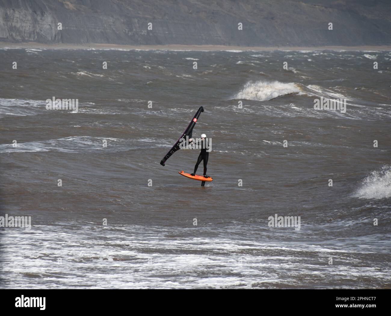 Un surfista alare scivola attraverso un mare mosso alimentato da una brezza rigida al largo della costa Jurrasic nella baia di Lyme. Dorset.UK Foto Stock