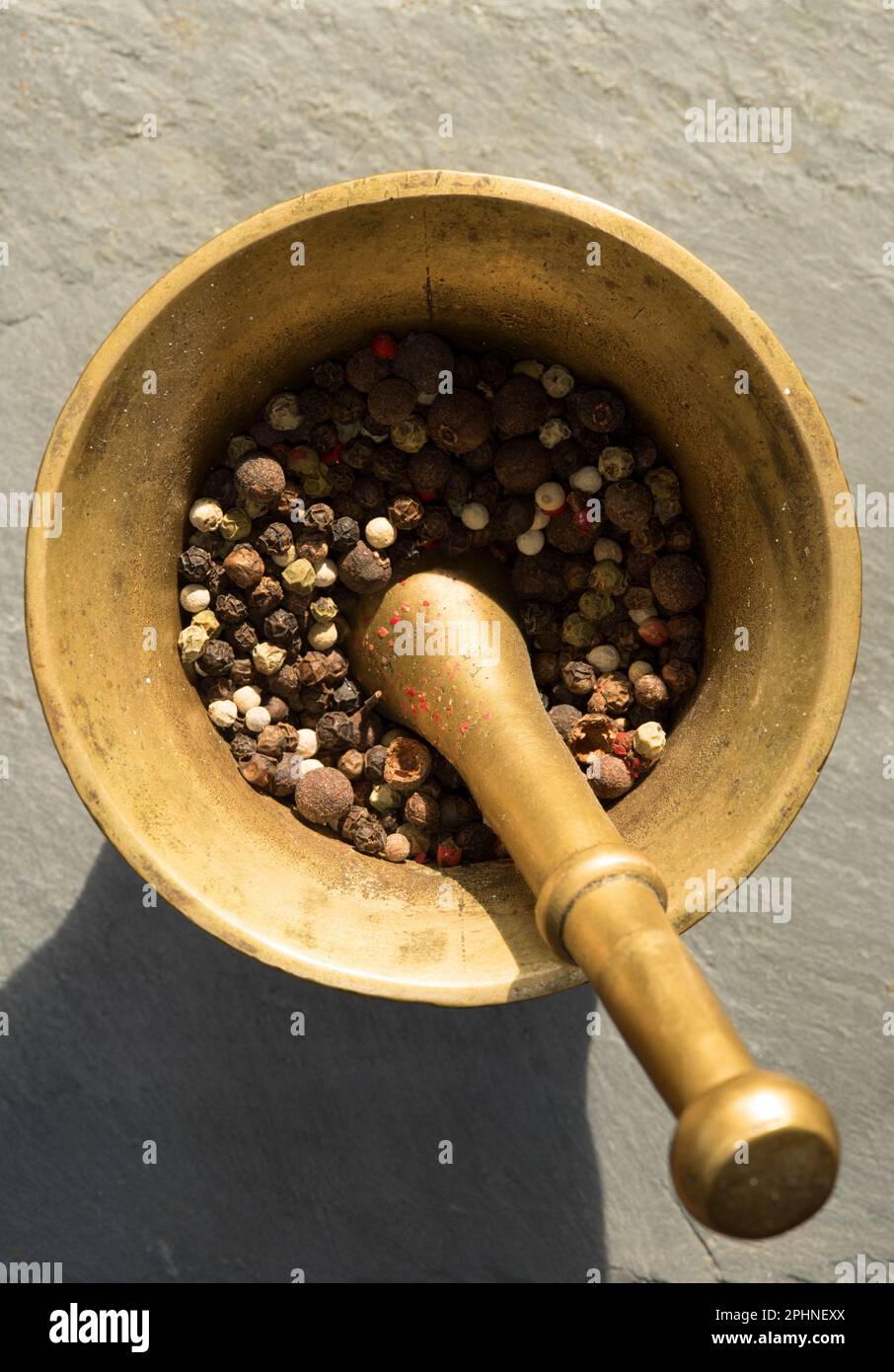 un mortaio con vari tipi di pepe colorato al suo interno Foto Stock