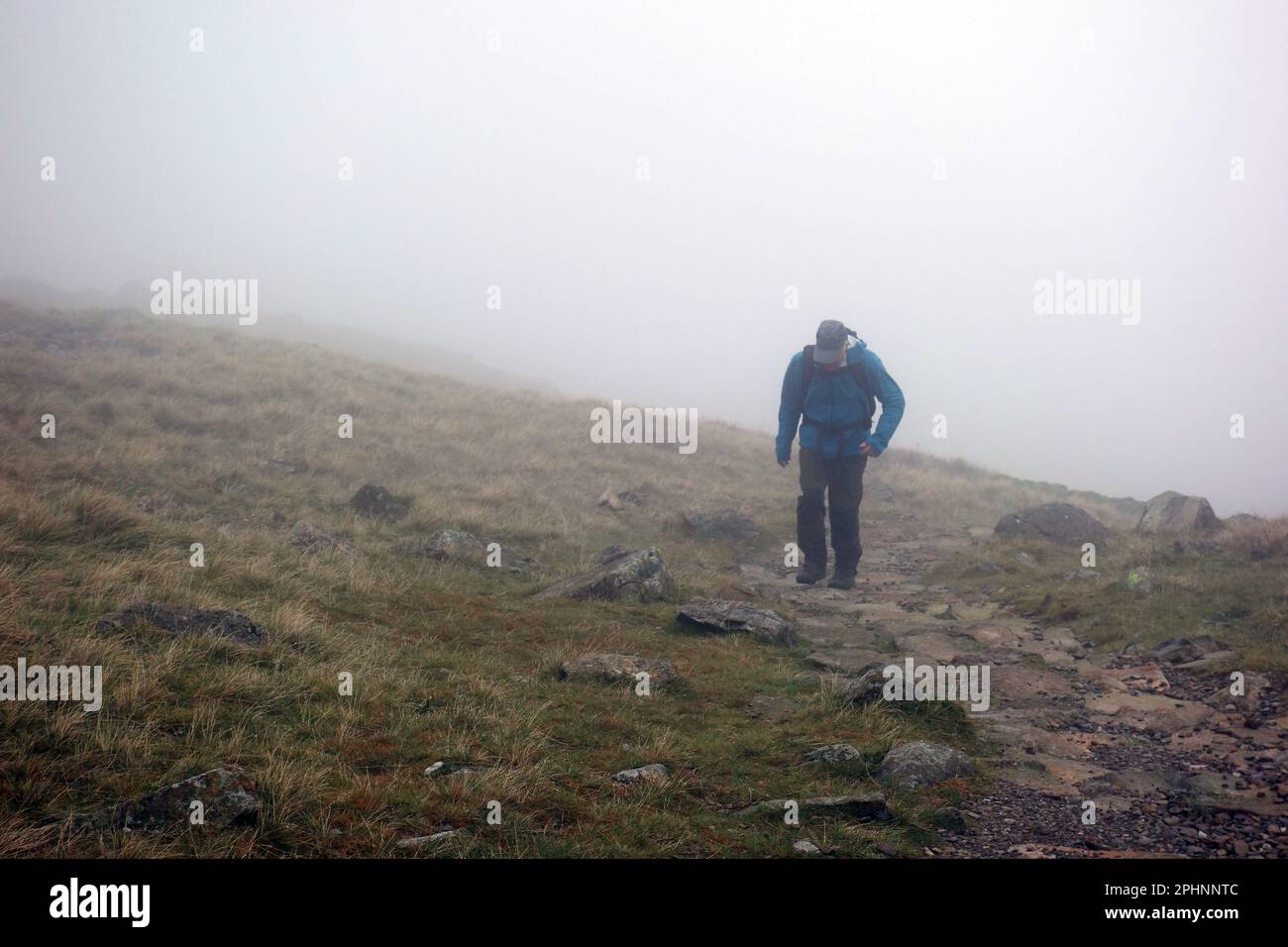 Man (Hiker) Walking in Low Cloud al vertice del Wainwright 'Grande fine' da Esk Hause a Borrowdale, Cumbria, Inghilterra, Regno Unito. Foto Stock