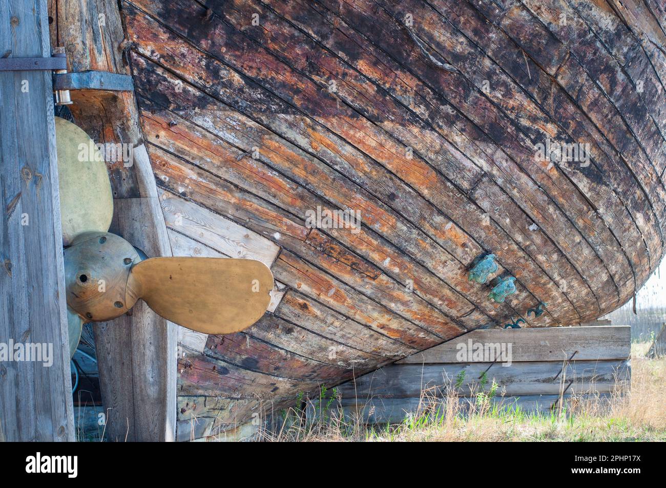 Un vecchio naufragio in legno abbandonato con un'elica in rame. Tavole di legno da vecchio scafo retrò barca. Foto Stock