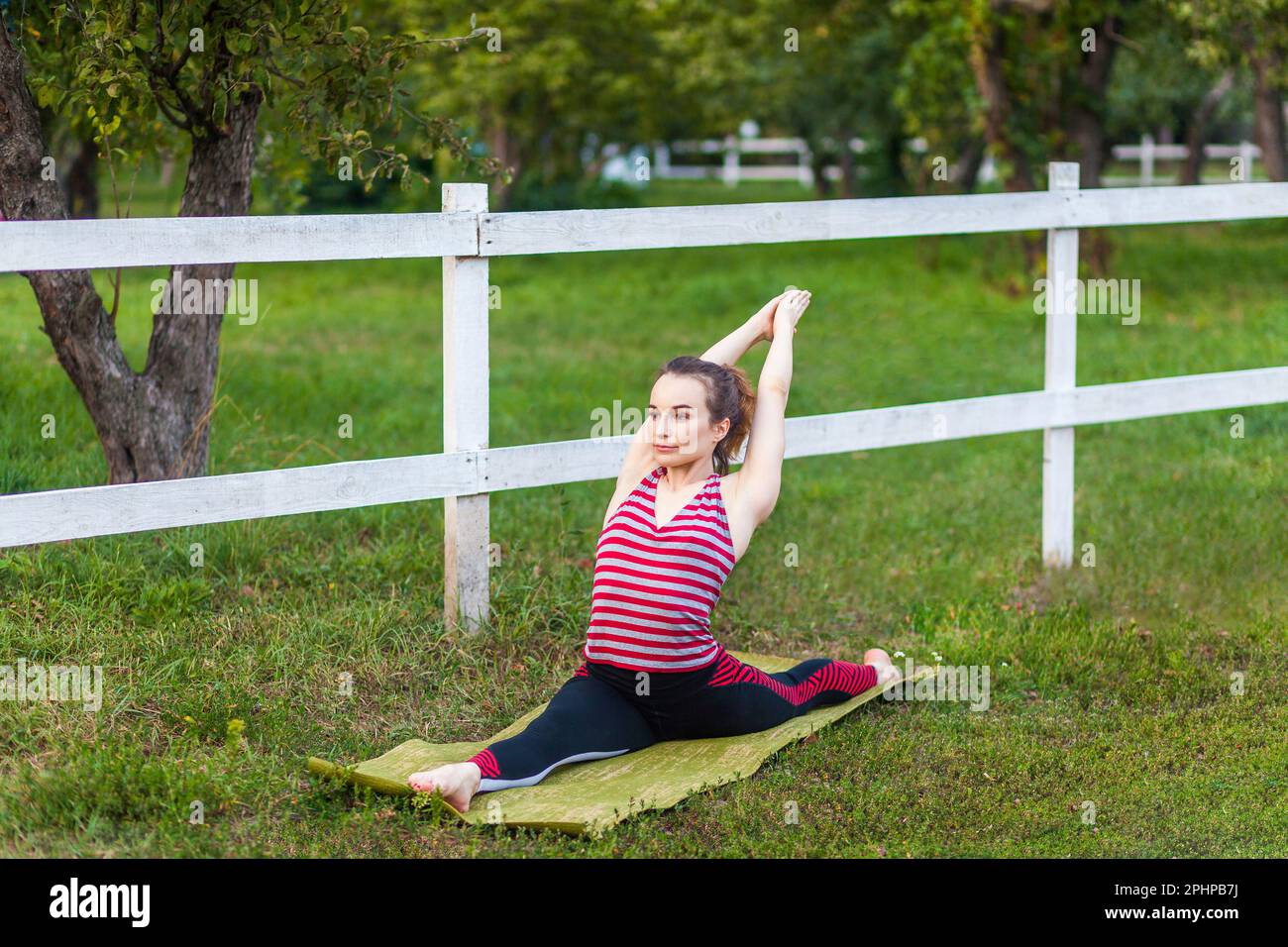 Hanumanasana posa. Ritratto completo di yoga atletica bella donna pratica yoga nel parco all'aperto, fare, Monkey God, seduta piano stendendo spezza gambe spezza spago posa, indossare abbigliamento sportivo. Foto Stock