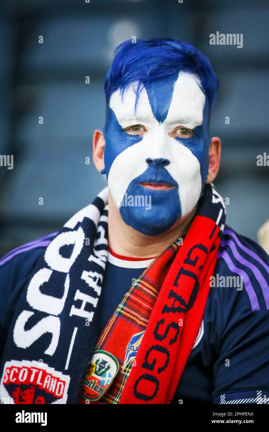 Tifoso della squadra di calcio scozzese con il volto dipinto con un abbigliamento scozzese e capelli di colore blu e una sciarpa scozzese, in presenza Foto Stock