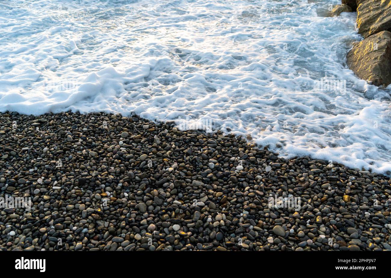 Onde di mare su fondo di spiaggia di ciottoli struttura. Acqua oceano trasparente, modello roccioso a riva, mockup estivo con spazio copia, costa di pietra, vacanza c Foto Stock