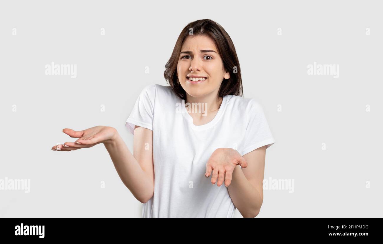 scioccato ritratto donna confusa alzando spalle Foto Stock