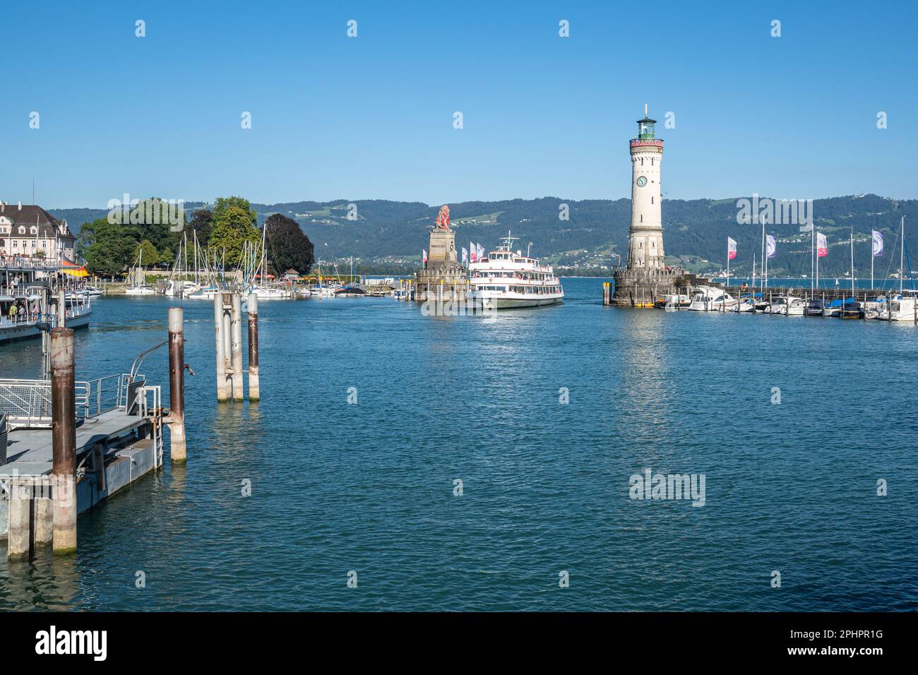 Un traghetto che entra nel porto di Lindau passando tra il faro e l'iconica scultura del Leone bavarese, Baviera, Germania Foto Stock
