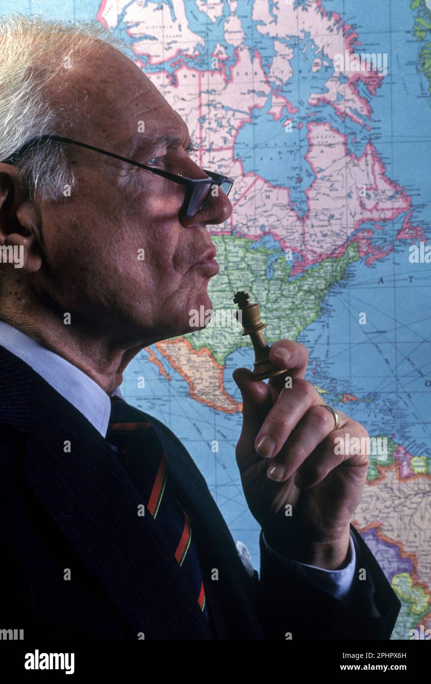 1990 STORICO UOMO D'UFFICIO SILHOUETTED OPERAIO A WORLD MAP (©RAND MCNALLY 1990) TENENDO IL PEZZO DI SCACCHI RE Foto Stock