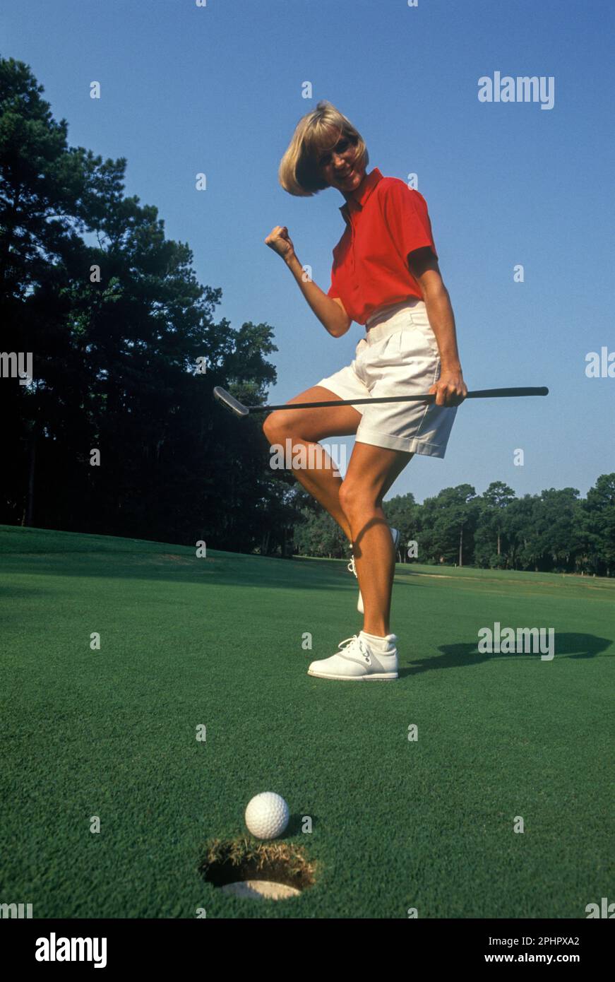 1990 Donna storico golfista dal foro sul putting green Foto Stock