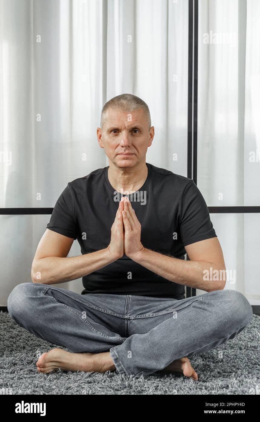 Il concetto di uno stile di vita sano. Ritratto di un uomo che medita in posizione loto su un tappetino yoga durante una pausa al lavoro. Foto Stock