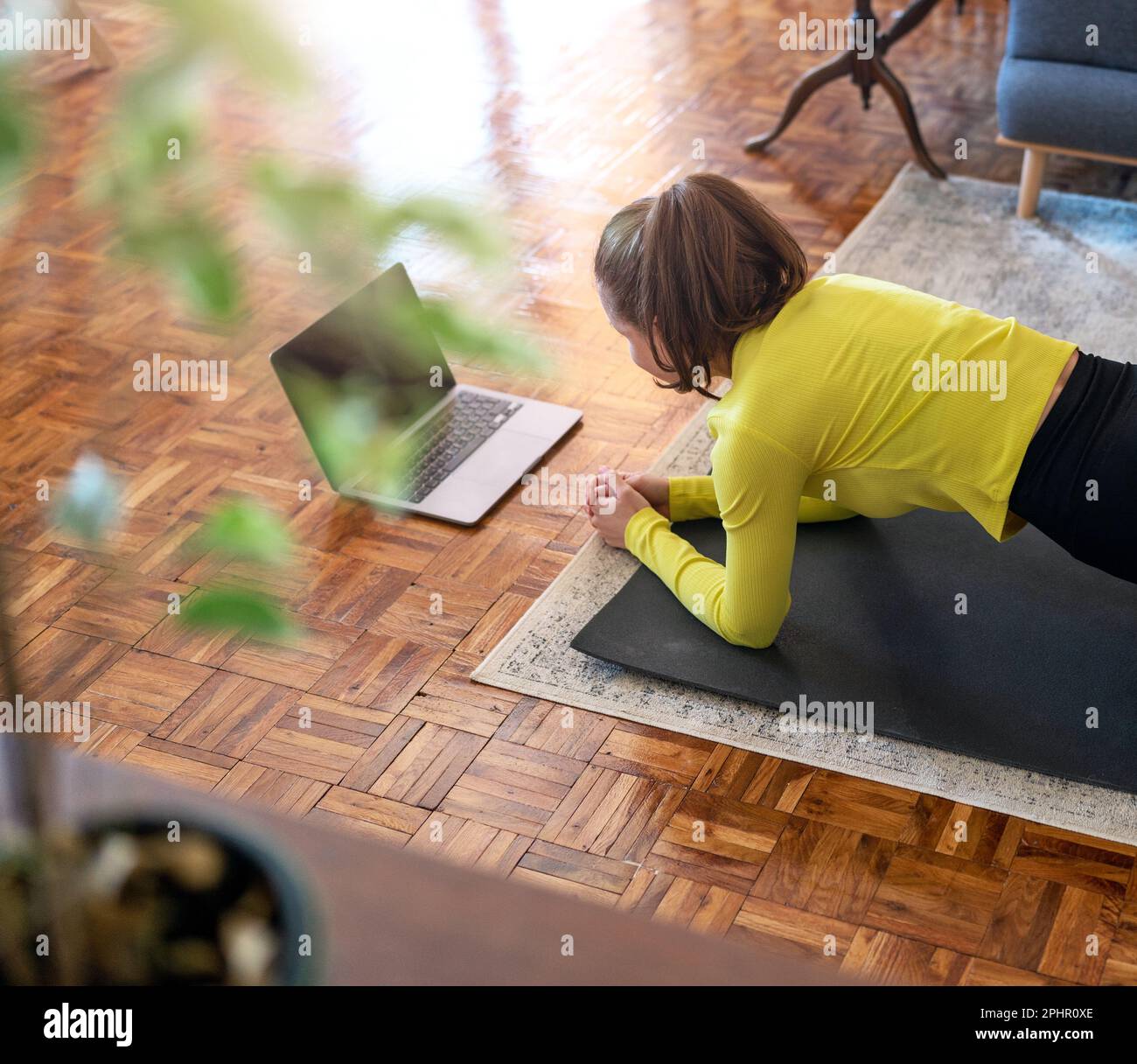 Formazione sportiva online a casa, donna che fa tavola e utilizzando il suo computer portatile. Foto Stock