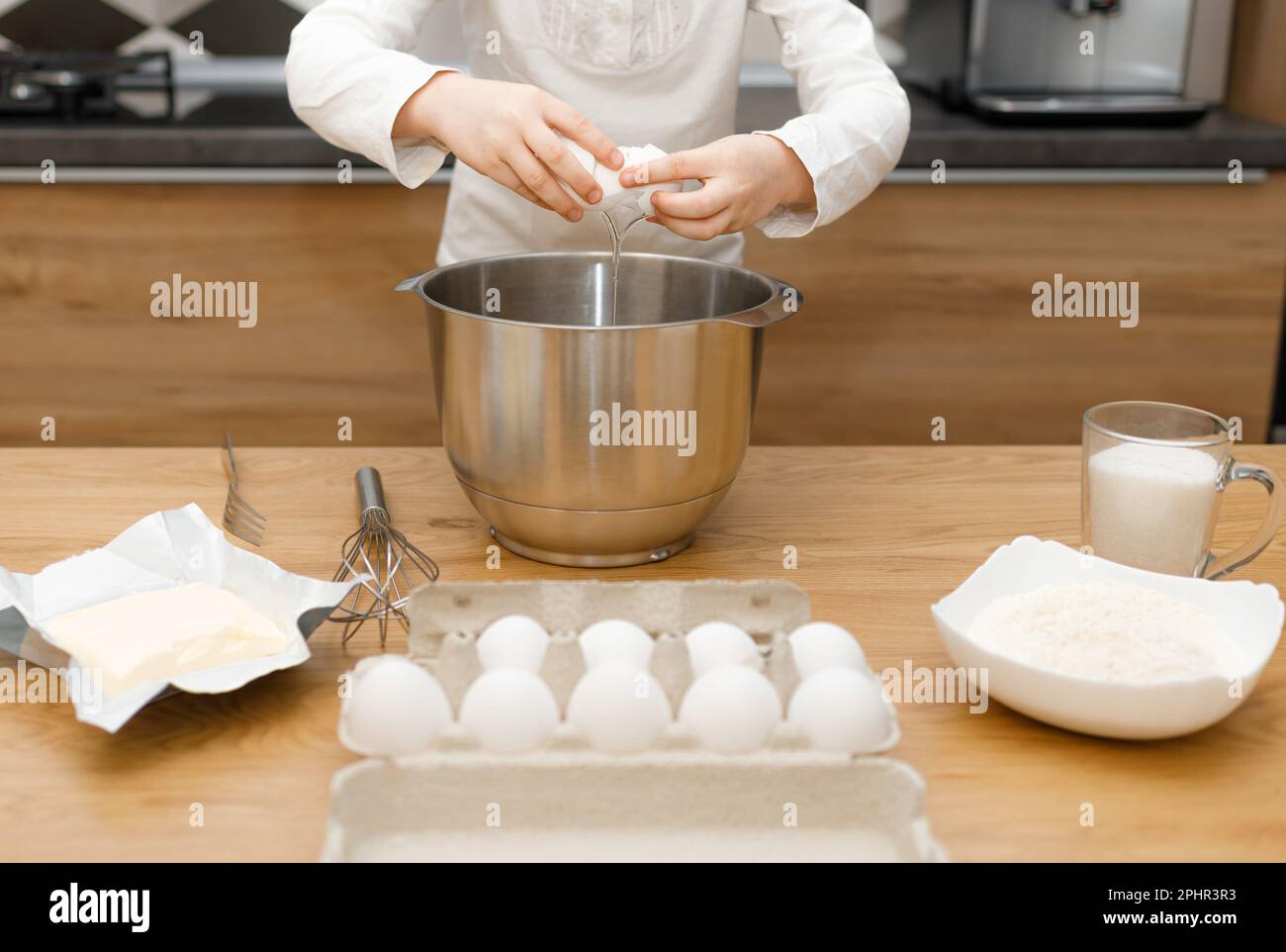 Mani di No viso bambino cracking, sbattere uovo, preparare e mescolare l'impasto in cucina moderna. Piccola ragazza d'aiuto. Tempo senza gadget Foto Stock