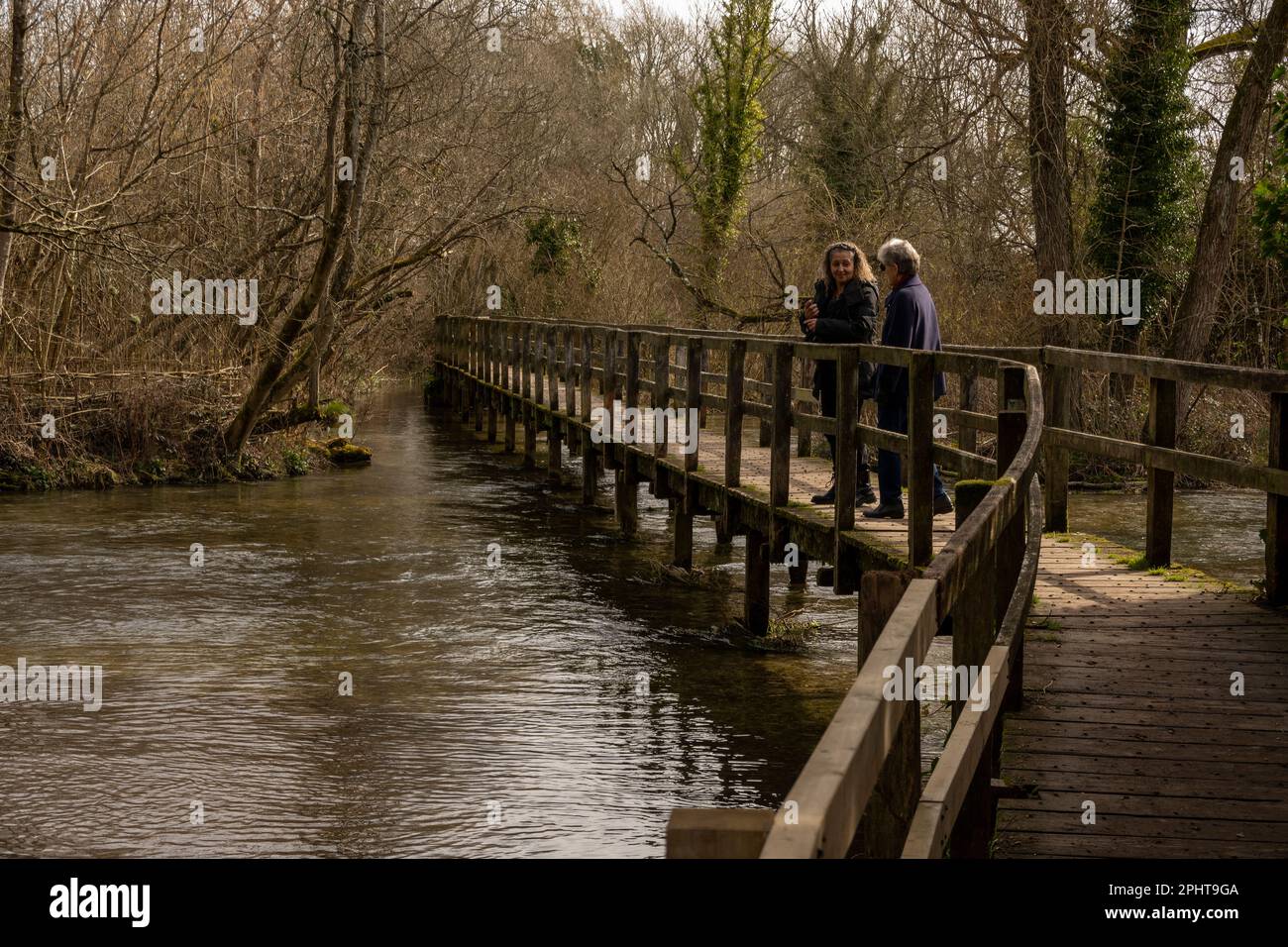 Wherwell, Hampshire, Inghilterra, Regno Unito. 2023. Due donne fanno una passeggiata invernale attraverso il famoso River Test a Wherwell. Famoso per la pesca alla trota. Foto Stock
