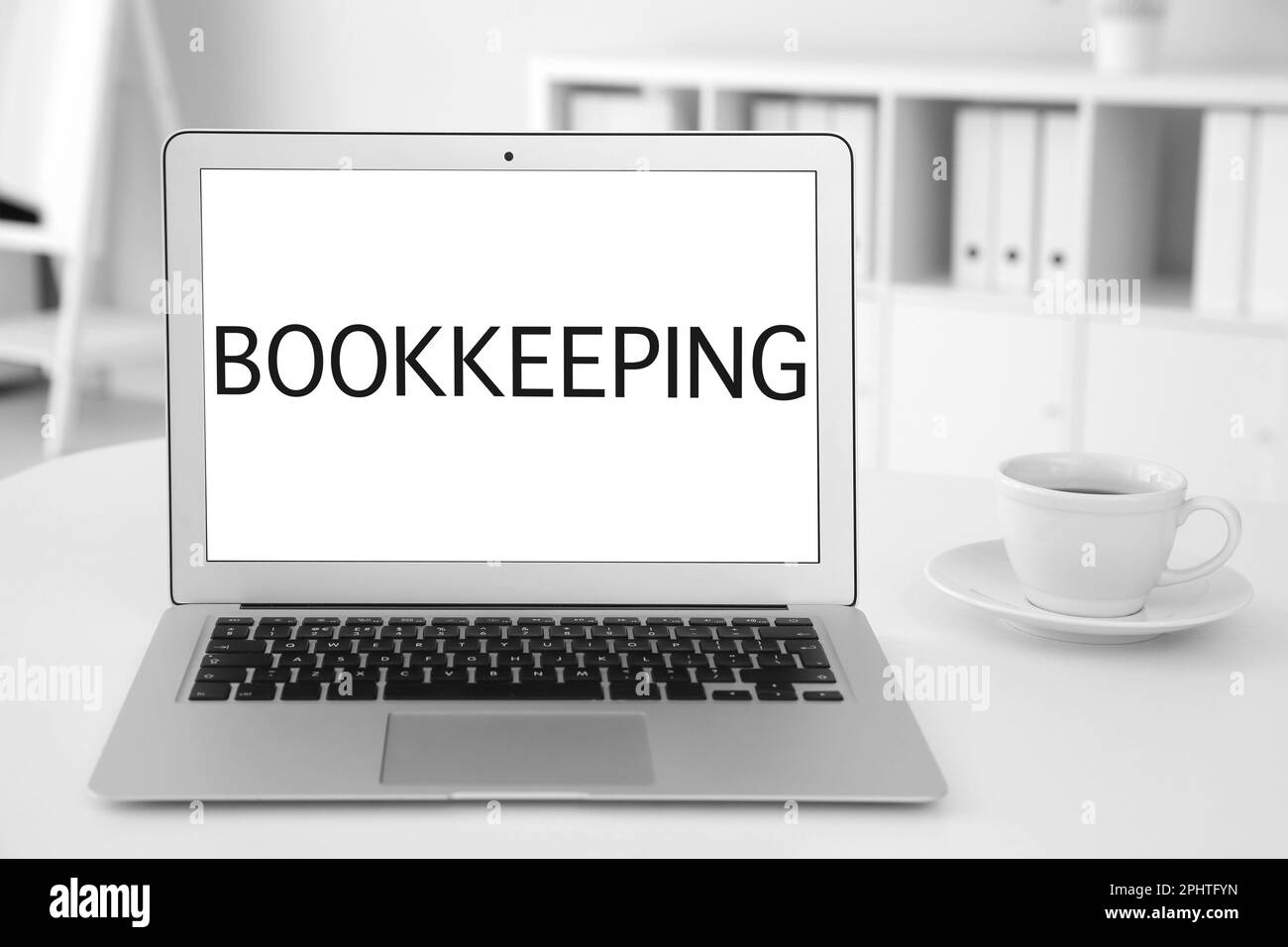 Concetto di contabilità. Moderno computer portatile e una tazza di caffè su un tavolo bianco in ufficio Foto Stock