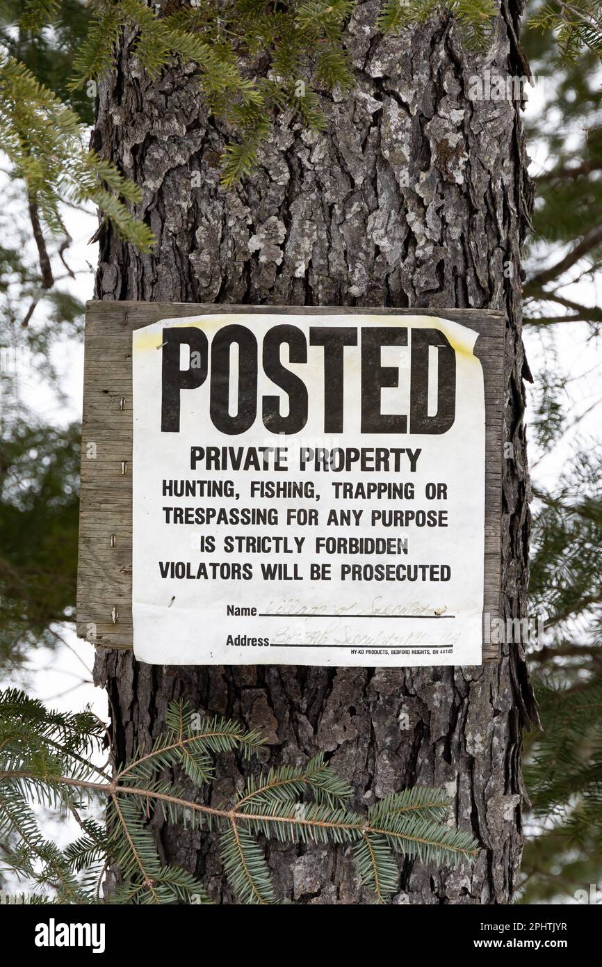 Un vecchio affisso sbiadito - proprietà privata - segno su un bordo inchiodato ad un albero nelle montagne di Adirondack, NY USA Foto Stock