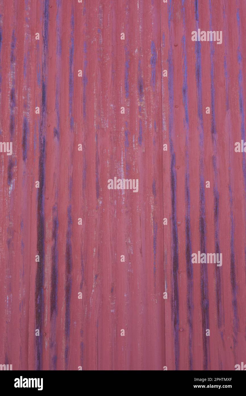 Pannello metallico corrugato rosso arrugato con striature scure. Sfondo a parete con texture. Stile vintage logoro e resistente alle intemperie. Concetto astratto. Foto Stock