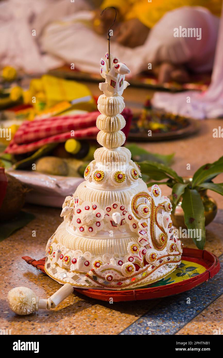 topor è un copricapo conico realizzato in sholapith bianco che viene indossato dallo sposo bengalese durante la tradizionale cerimonia di nozze indù bengalese o rituali. Foto Stock