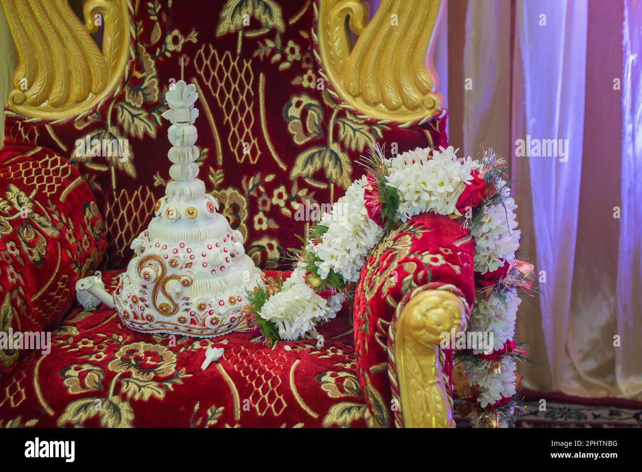 Topor e ghirlanda tenuti su sedia decorata dello sposo bengalese simbolo del matrimonio bengalese. topor è un copricapo conico realizzato in sholapith bianco che è Foto Stock